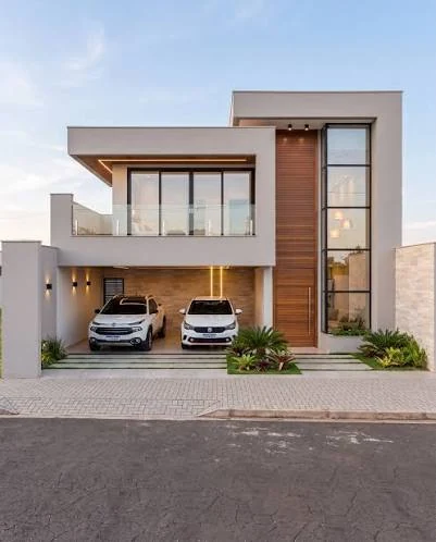 Fachada residencial com volumetria de platibandas e volumes e canteiros com plantas junto à calçada